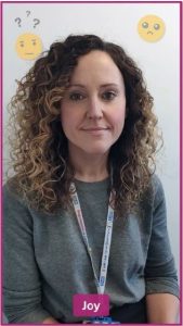 A nurse with curly hair wearing an NHS lanyard